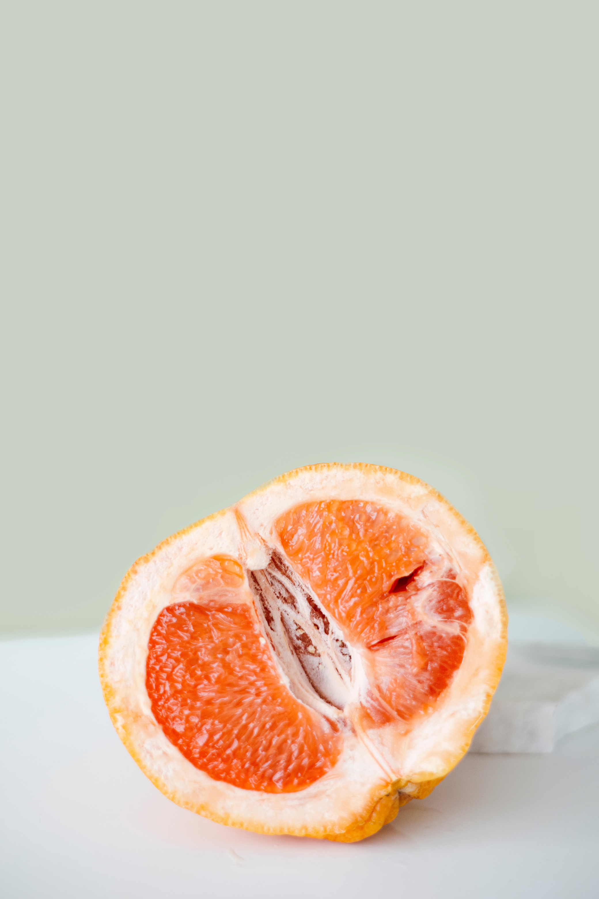 A Slice of Grapefruit on White Surface